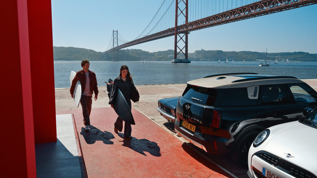 Ludzie i samochody MINI na tle mostu.